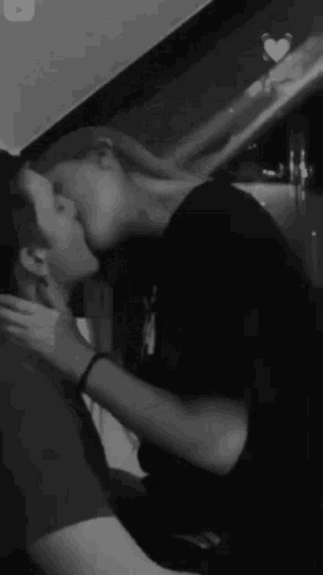 a black and white photo of a woman kissing a man .