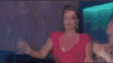 a woman in a pink dress is dancing in a room with a green light behind her .