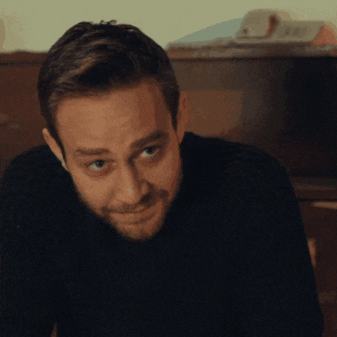 a man wearing a black sweater is looking at the camera