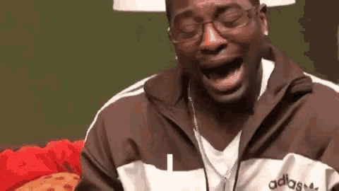 a man wearing glasses and a adidas jacket is crying .