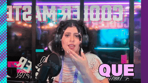 a woman wearing headphones stands in front of a microphone with the word que in the corner