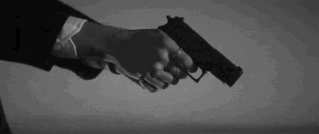a man in a suit is holding a gun in his right hand .