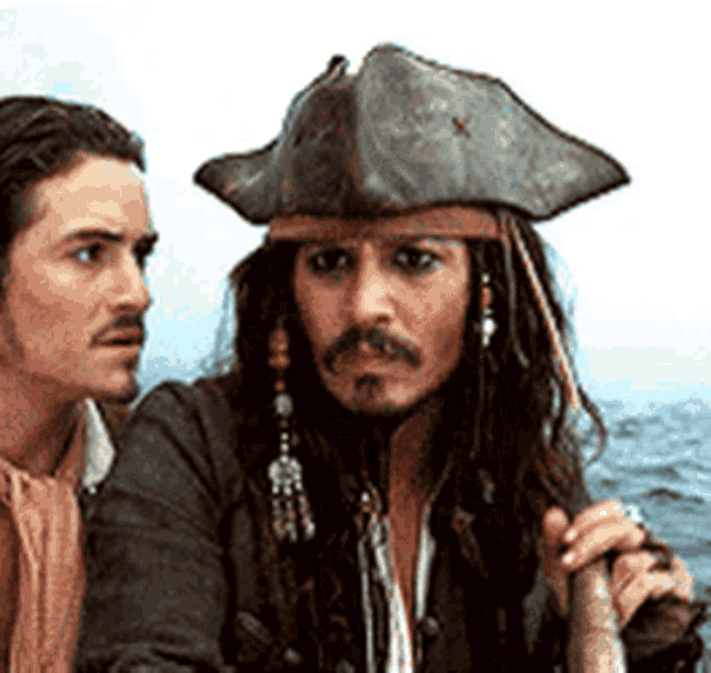 a man in a pirate hat looks at another man