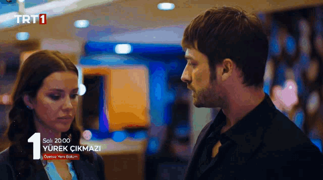 a man and a woman are looking at each other and the number 1 is on the screen
