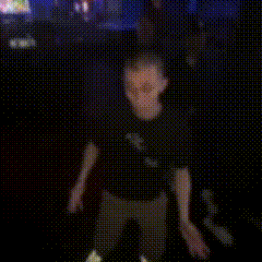 a blurry picture of a man in a black shirt walking in a dark room .