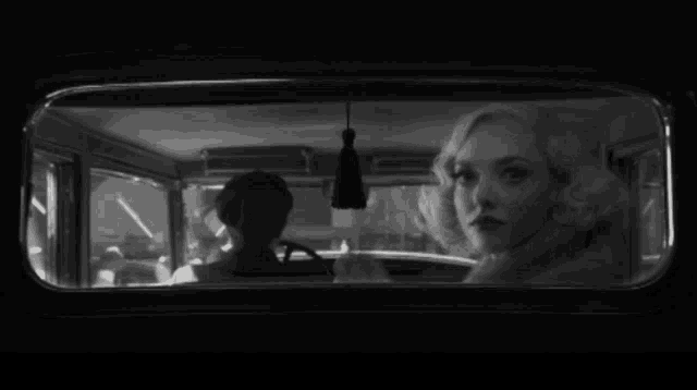 a black and white photo of a woman looking out of a car window