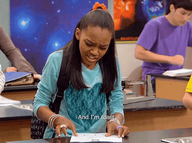 a girl sitting at a desk with the words " and i 'm toast " written on a piece of paper