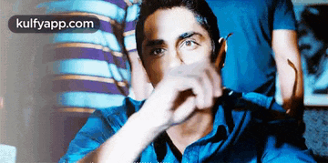 a man in a blue shirt is covering his face with his hand and the words kulfyapp.com are visible in the corner