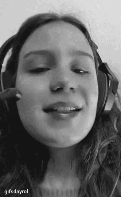 a black and white photo of a girl wearing headphones with gifsdayrol written below it