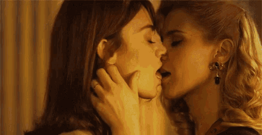 a close up of two women kissing with one wearing a necklace with the number 3 on it