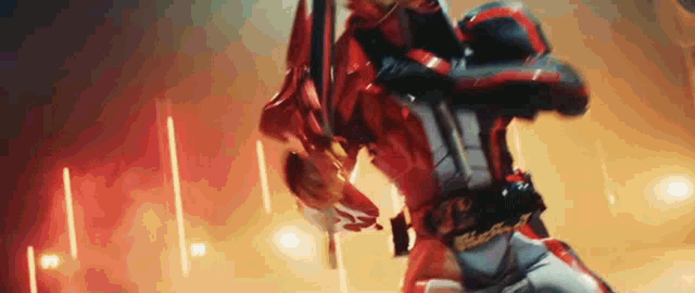 a man in a red and black suit is holding a sword in his hand .