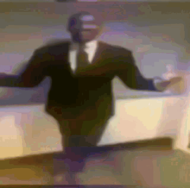 a man in a suit and tie is dancing with his arms outstretched
