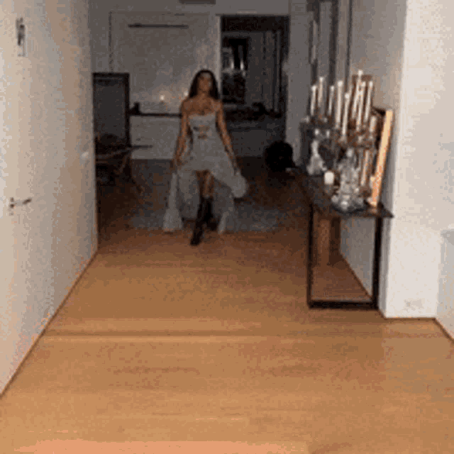 a woman in a white dress is walking through a hallway