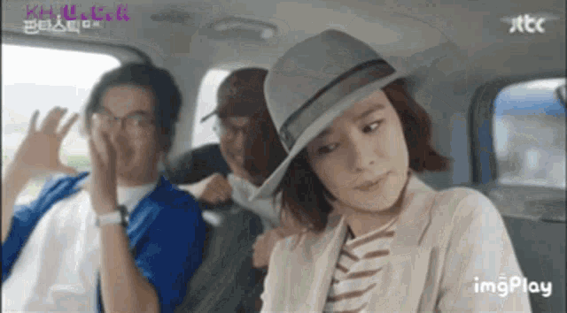 a woman in a hat is sitting in the back seat of a car with other people