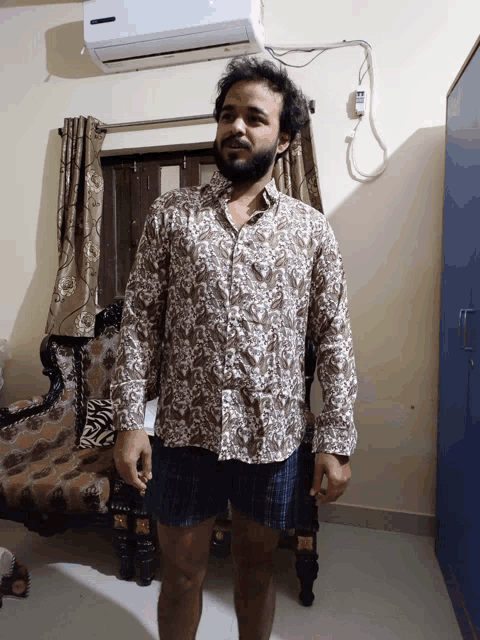 a man in a floral shirt is standing in front of a samsung air conditioner
