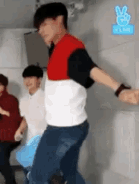 a man in a red , white and black shirt is dancing in a room with other people .