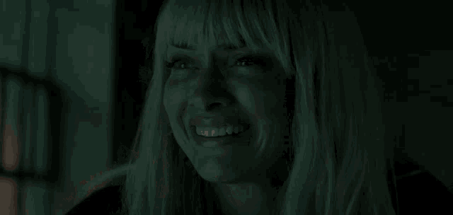 a woman with blonde hair and bangs is sitting in a car in the dark .