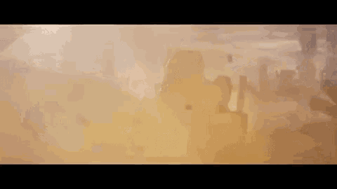 a soldier is walking through a cloud of dust in a desert .