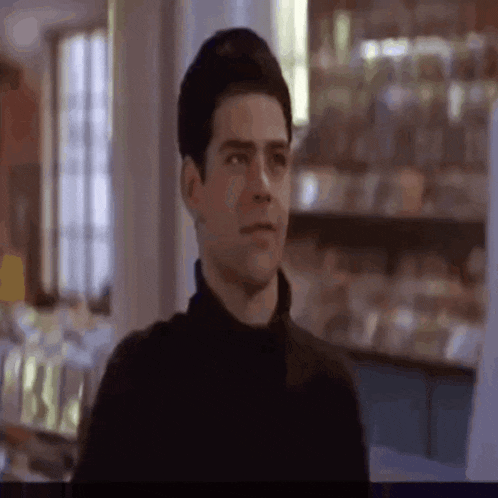 a man in a black turtleneck is standing in a room