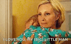a woman is holding a baby in her arms and saying `` i love you , my ( big ) little man '' .