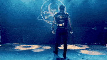 a man stands in front of a skull and crossbones logo
