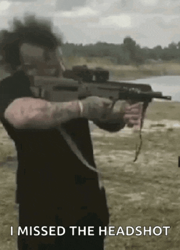 a man is holding a rifle in a field with the words `` i missed the headshot '' written on the bottom .