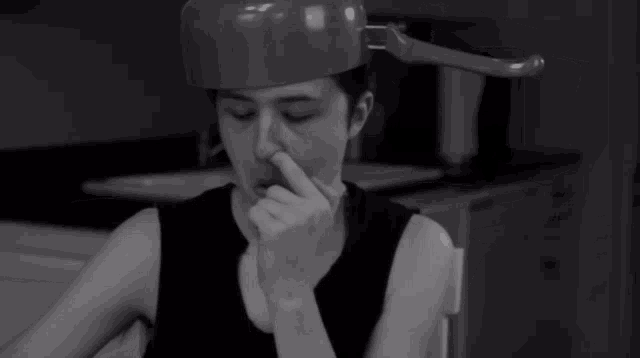 a black and white photo of a person covering their nose with their hand