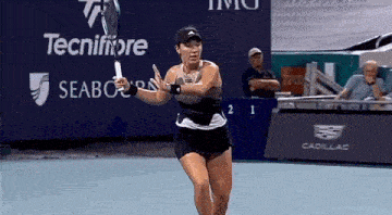 a woman is swinging a tennis racquet on a tennis court in front of a sign that says tecnifibre