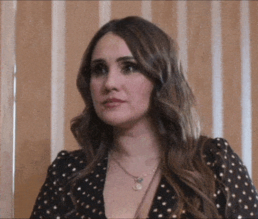 a woman wearing a black and gold polka dot top and a necklace