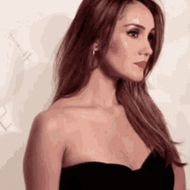 a woman in a black strapless dress is looking to the side .