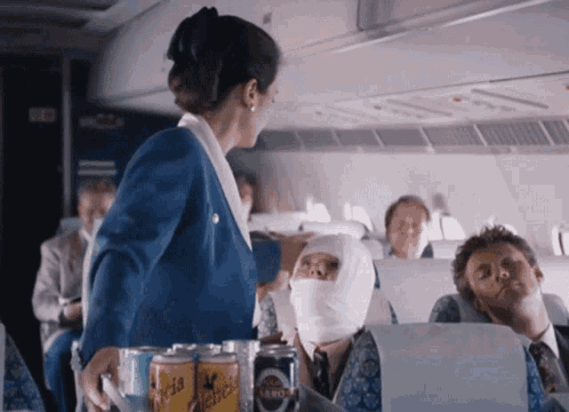 a stewardess on a plane is serving a man with a bandaged head a can of schweppes