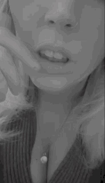 a woman with a nose ring and a necklace is biting her finger