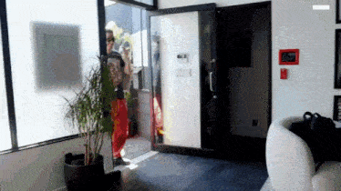 a man in red pants is standing in front of a door