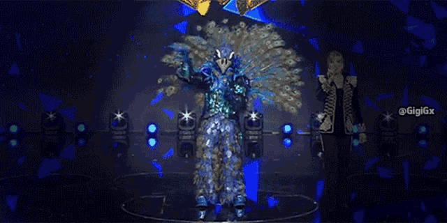 a person dressed as a peacock is standing on a stage .