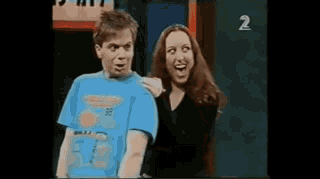 a man and a woman are standing next to each other on a stage . the woman is making a funny face .