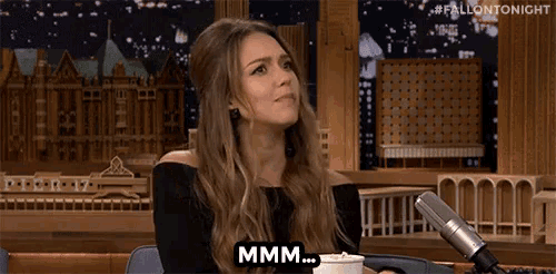 a woman is sitting in front of a microphone with a cup of coffee and says mmmm .