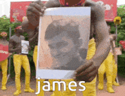 a man in yellow pants is holding a picture of a man with the name james on it