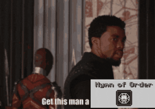 a man with a beard is standing next to another man with a sign that says get this man a hymn of order