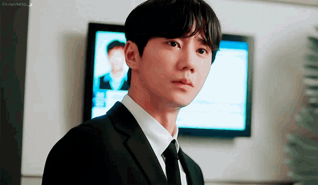 a man in a suit is crying in front of a tv