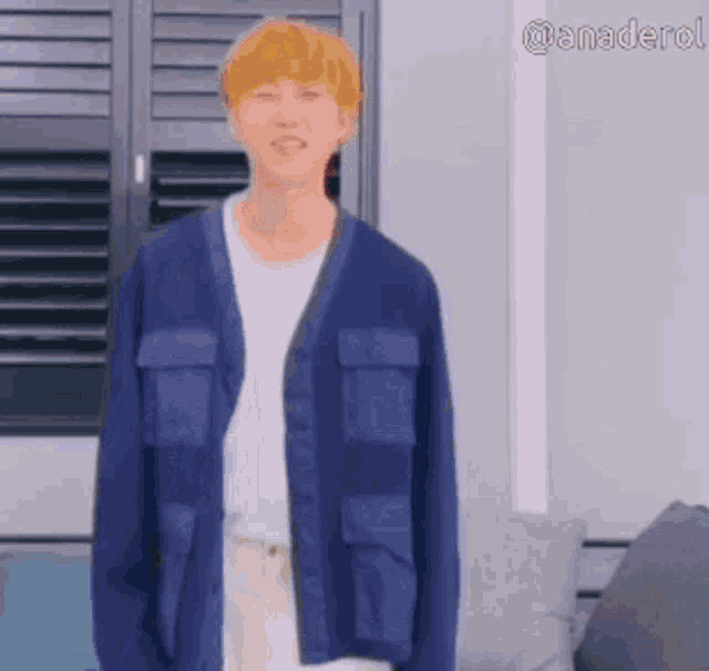 a man wearing a blue cardigan and a white shirt is standing in a living room .