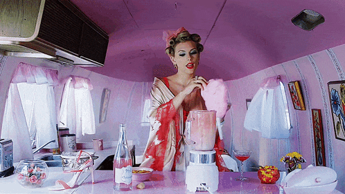 a woman in a red robe is making a pink drink