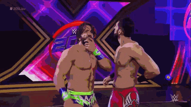 two wrestlers are standing next to each other in front of a purple and pink background with the letters w on it