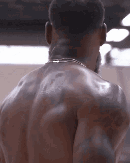 a man without a shirt is standing in a gym and looking at the camera .