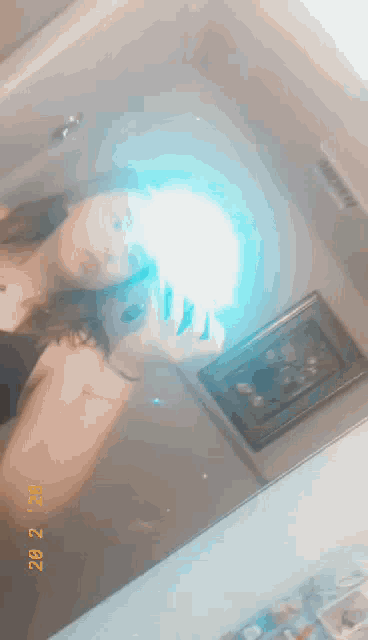 a woman is taking a selfie in front of a mirror with a blue light coming out of her hand .