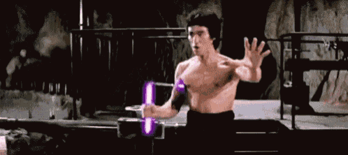 a man without a shirt is holding a purple light saber in his hand .