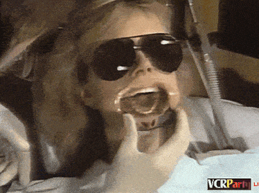 a woman wearing sunglasses is getting her teeth examined by a dentist with a vcrparty logo in the corner