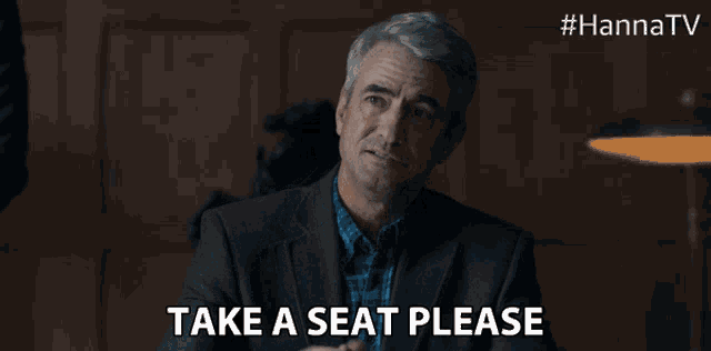 a man says take a seat please in a dark room