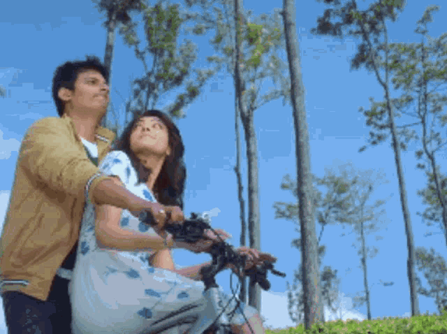 a man and a woman are riding a bicycle together