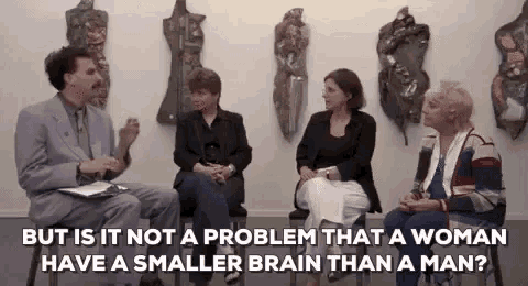 a man and three women are sitting in a room with a man talking to them .