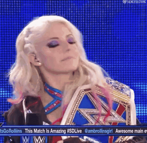 a female wrestler is holding a wrestling championship belt while standing on a stage .